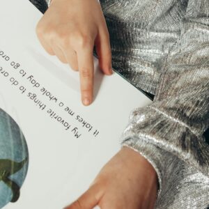 A child pointing to text in an illustrated book, showcasing reading and learning.